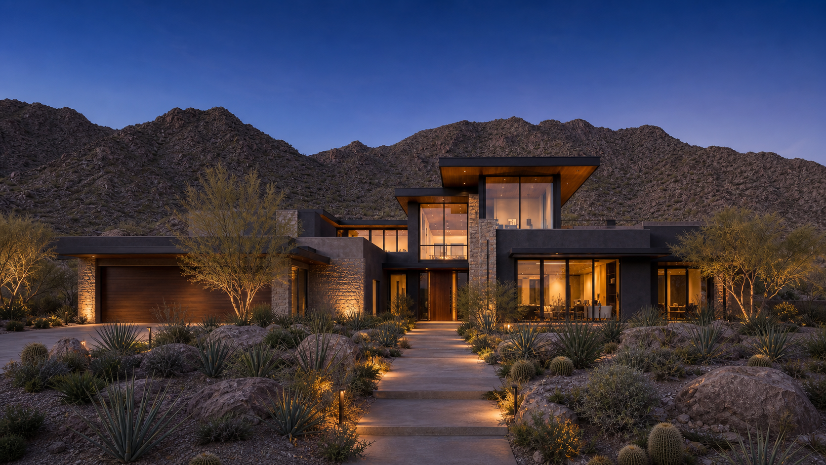 Wide landscape view of a signature Coachway modern desert residence beneath the mountains at twilight